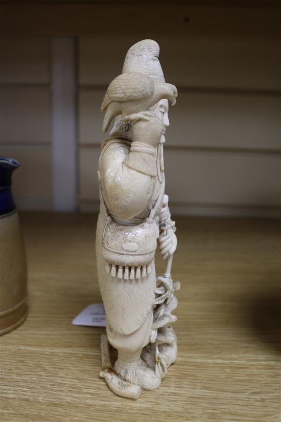 A Japanese carved ivory okimono of a huntsman, Meiji period, holding a hawk and a brace of birds